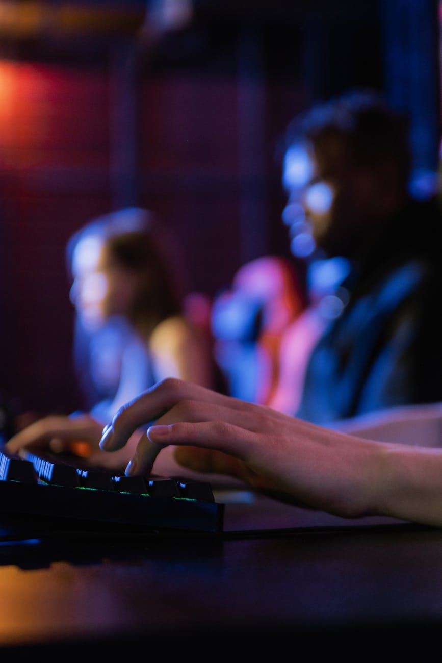 pexels-photo-7862515-7862515 Close-up of hands typing on a keyboard during an intense gaming session in a dimly lit room.
